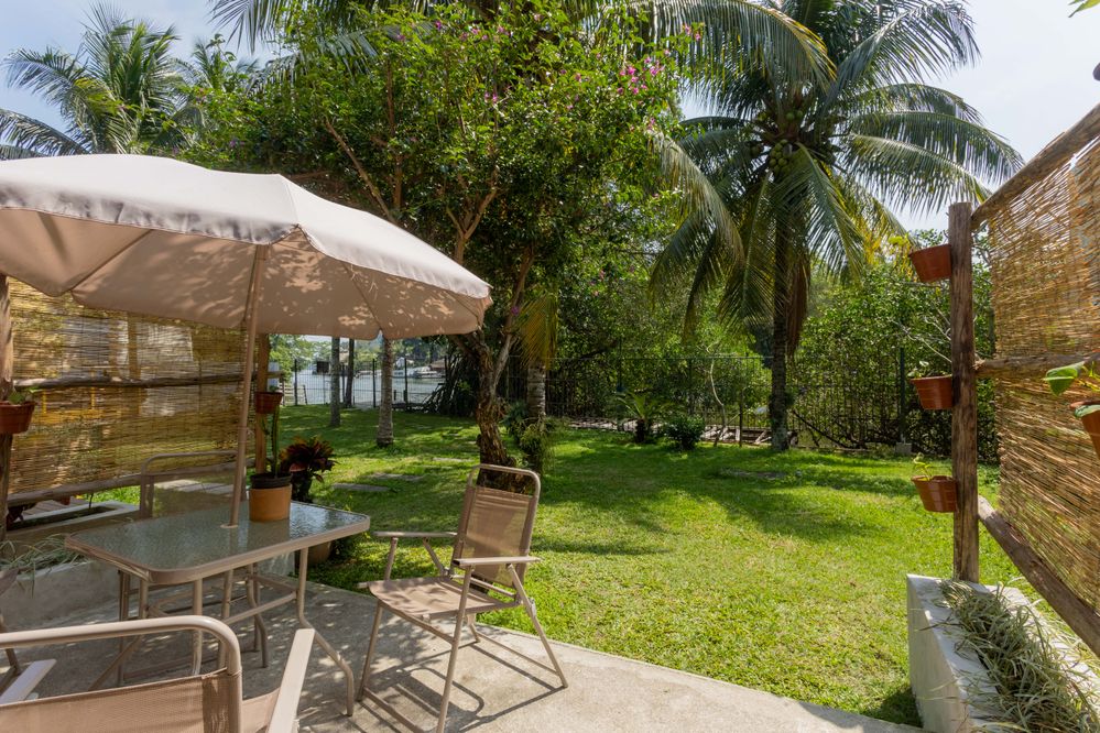 Patio com muitas plantas, móveis e vista para a lagoa e as montanhas