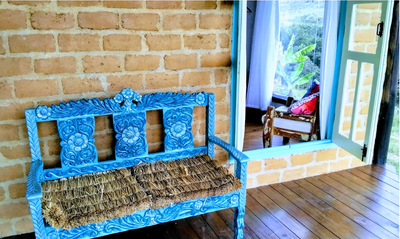 Next to the reforestation wood floor and the adobe wall, an old and handcrafted bench rescued from the rubble of an antique shop. With a charming painting and straw seats, it was a grace on the porch.